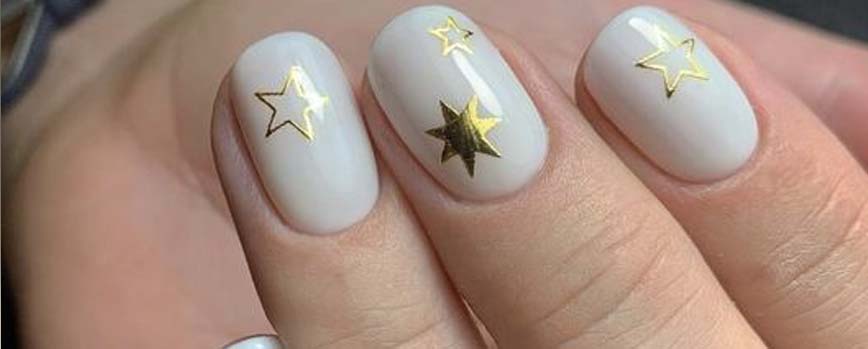 Uñas blancas decoradas con estrellas doradas