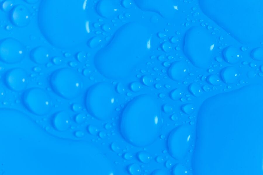 Vista superior en primer plano del fondo borroso húmedo azul oscuro con gotas de fluido transparentes abstractas aún brillantes de diferentes tamaños y formas
