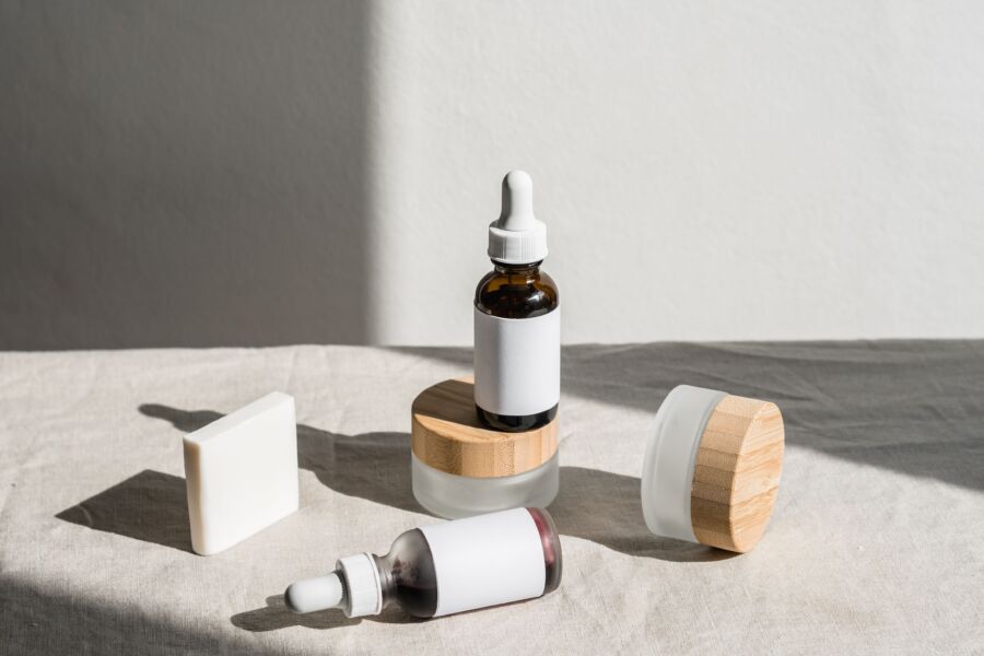 Un bodegón minimalista de botellas y frascos cosméticos con iluminación natural, que enfatiza el diseño de productos de belleza.