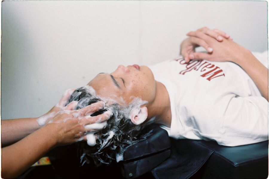 Una persona que disfruta de un lavado de cabello relajante en un salón de belleza, transmitiendo relajación.