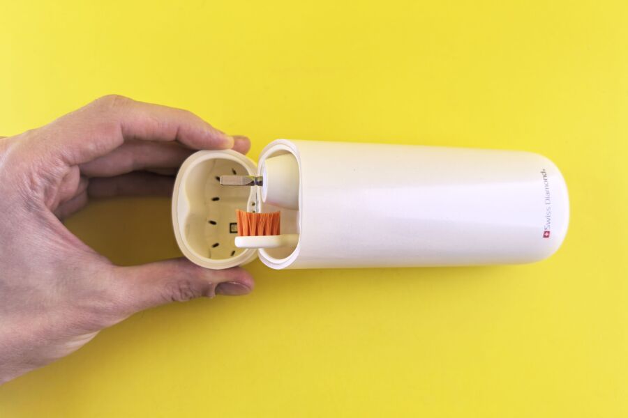 Un elegante cepillo de dientes eléctrico portátil con una elegante funda protectora contra un vibrante fondo amarillo.