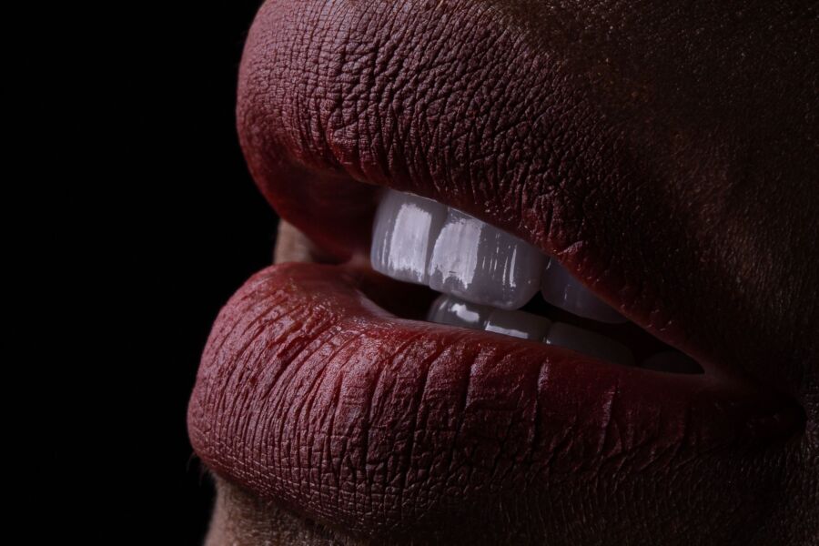 Un primer plano detallado de los labios con lápiz labial rojo y dientes blancos, destacando la textura y la expresión.