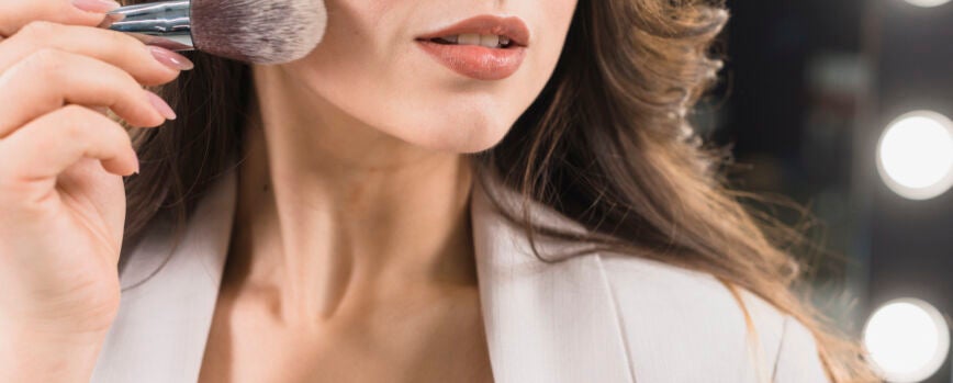 Hermosa mujer aplicando polvo con pincel de maquillaje