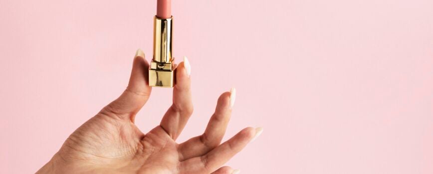Mano que sostiene el lápiz labial rosa de cerca