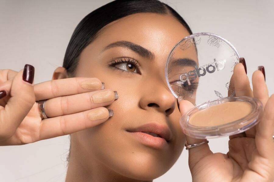 Primer plano detallado de una mujer aplicando base de maquillaje usando un compacto.
