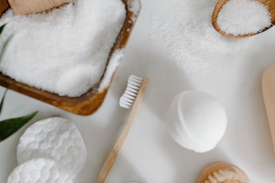 Colocación plana de elementos esenciales naturales para el baño, como un cepillo de dientes, sal y una bomba de baño.