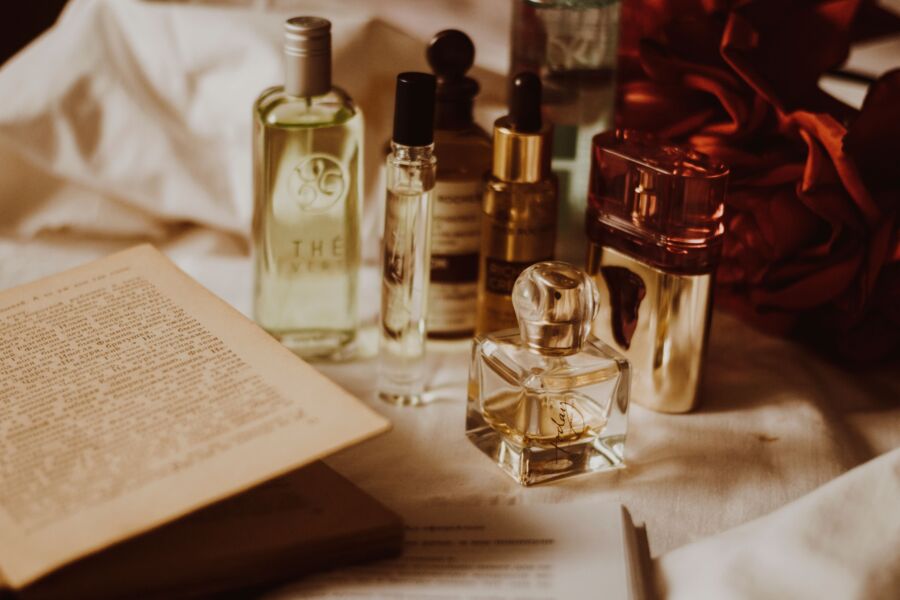 Bodegón estético de frascos de perfume surtidos y un libro abierto sobre una mesa.