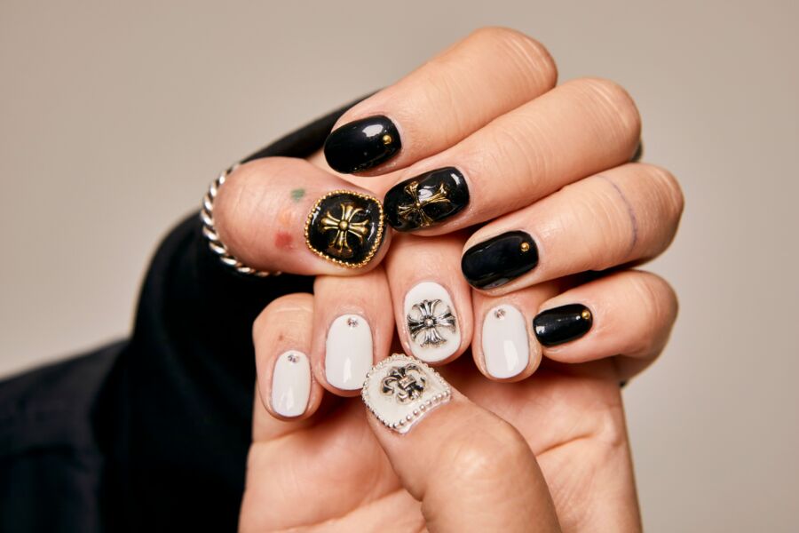 Primer plano de manos de mujer mostrando arte artístico de uñas en blanco y negro con adornos ornamentados.
