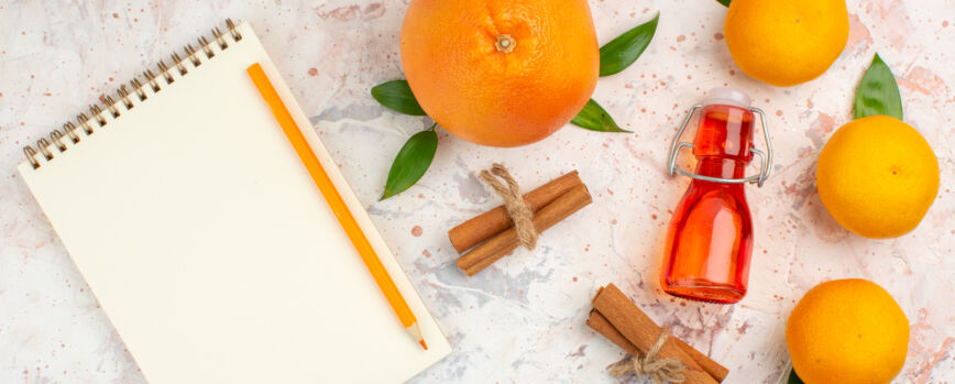 Vista superior mandarinas frescas palitos de canela botella naranja un lápiz un cuaderno sobre una superficie brillante