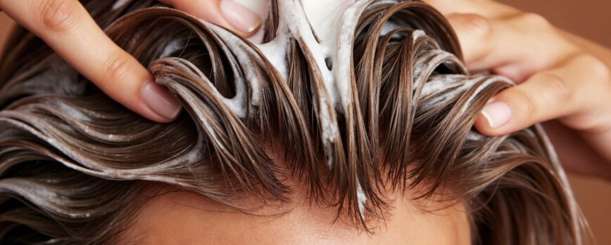 Mujer aplicando champú a su cabello