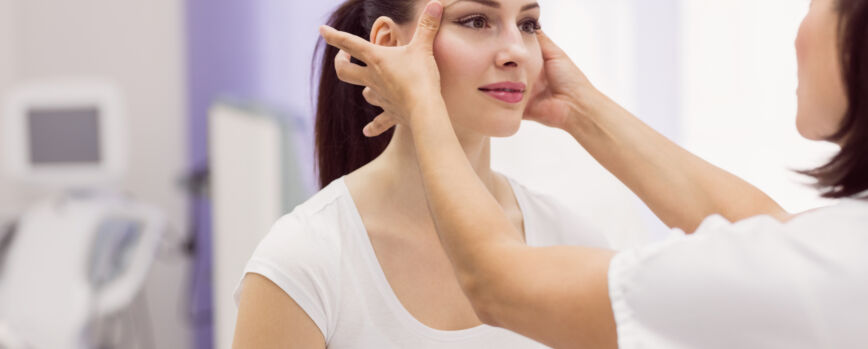 Dermatólogo examinando la piel del paciente femenino