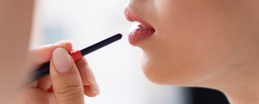 Cerrar mujer aplicando lápiz labial