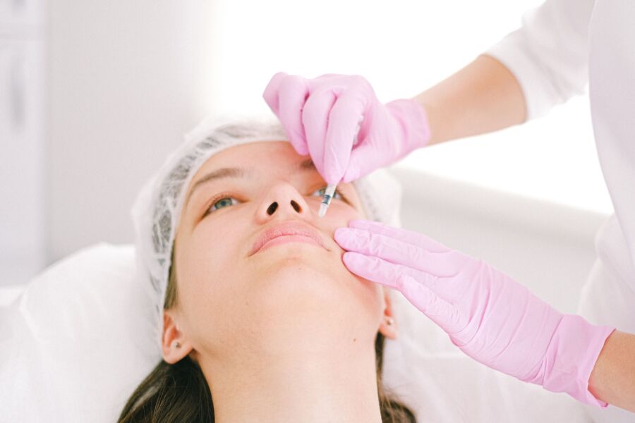 Mujer que recibe una inyección cosmética facial en un entorno clínico profesional.