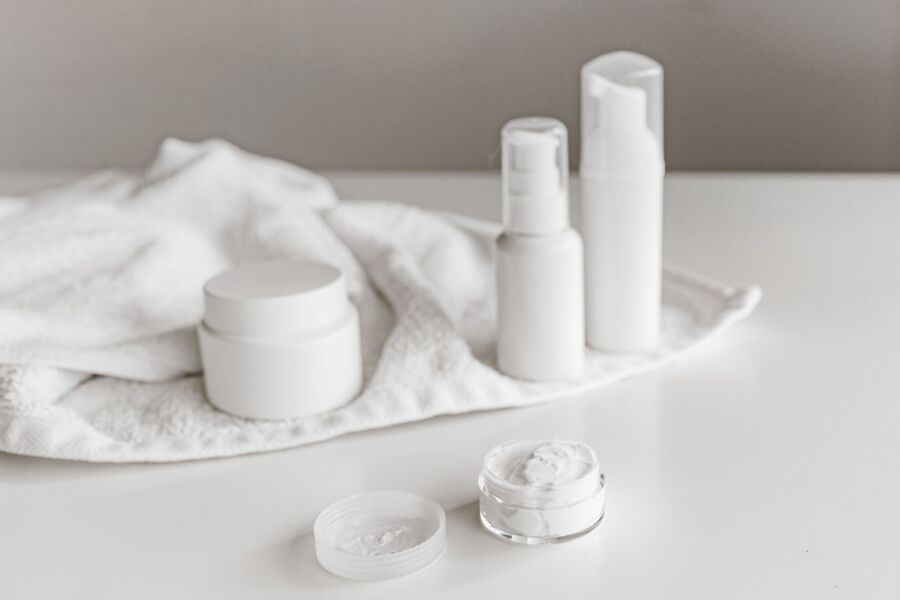 Exposición elegante de productos para el cuidado de la piel sobre una superficie blanca, destacando la simplicidad y la pureza.