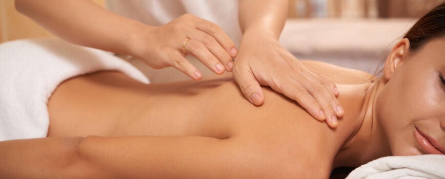 Mujer joven recibiendo masaje de espalda en el salón de spa