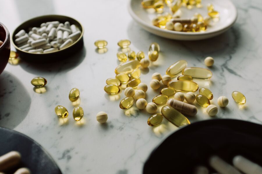 Un primer plano de píldoras y suplementos variados dispuestos sobre una superficie de mármol, destacando temas de salud y bienestar.