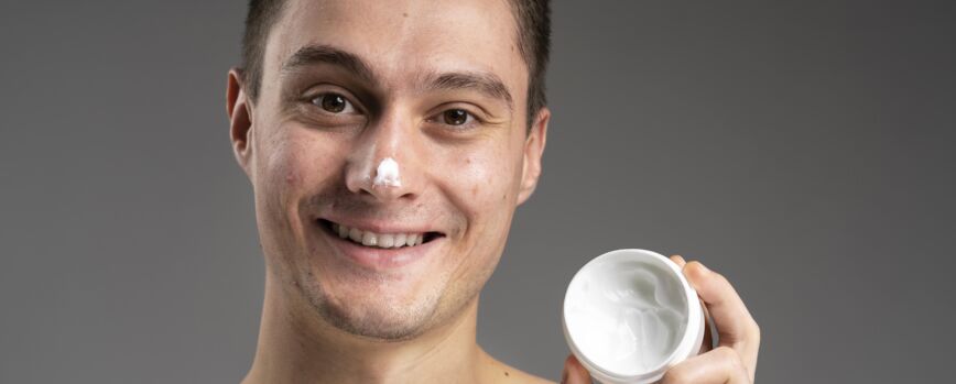 Hombre guapo joven con una crema para el acné