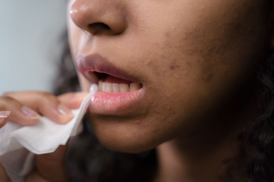 Primer plano detallado de una mujer limpiándose los labios, mostrando la textura y el cuidado de la piel.