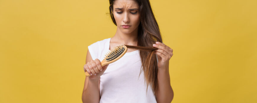 Mano de mujer sosteniendo su cabello largo con mirar las puntas dañadas de los problemas de cuidado del cabello