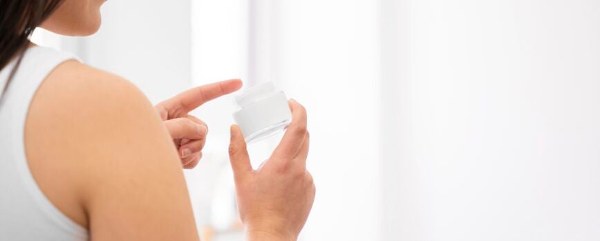Mujer de primer plano con envase de crema