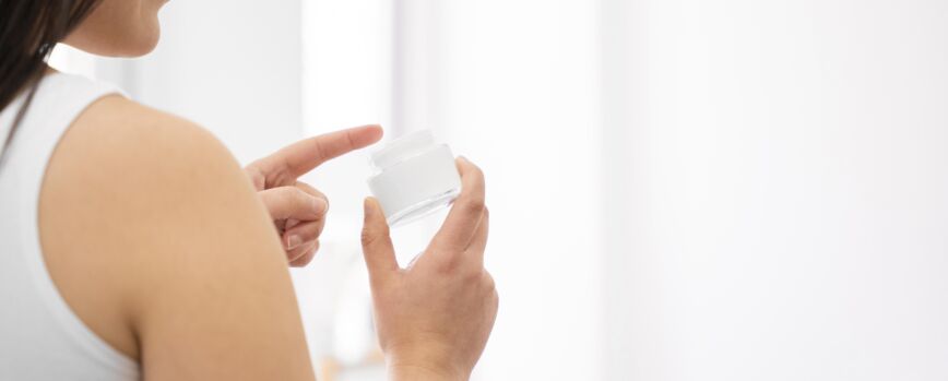 Mujer de primer plano con envase de crema