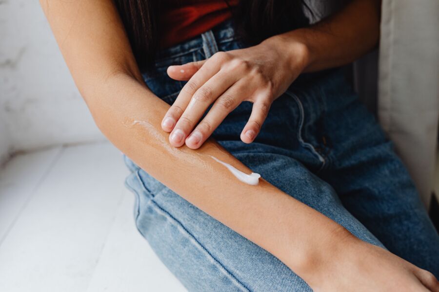 Primer plano detallado de una persona que se aplica crema en el brazo para la rutina de cuidado de la piel.