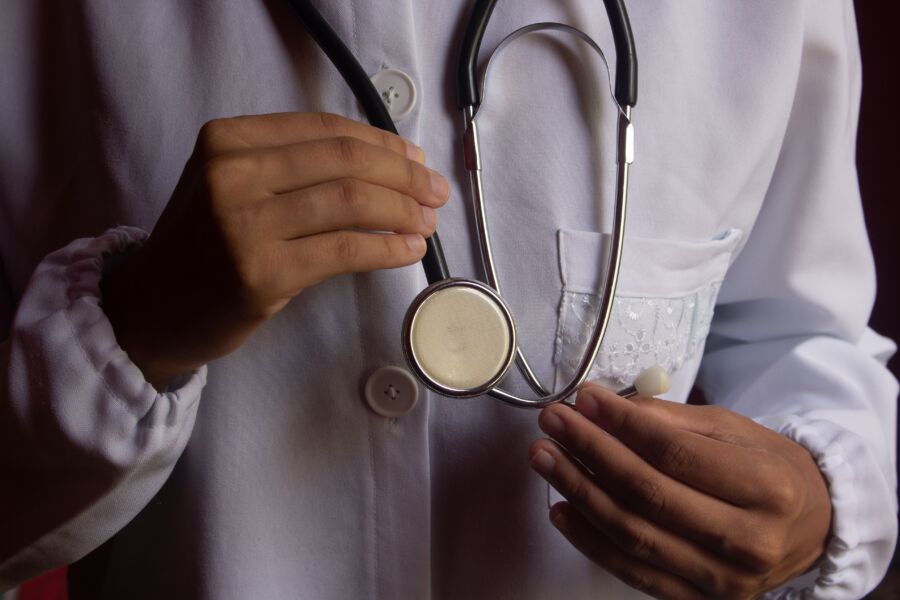 Una imagen en primer plano de un médico con una bata de laboratorio blanca sosteniendo un estetoscopio, que simboliza la atención médica.