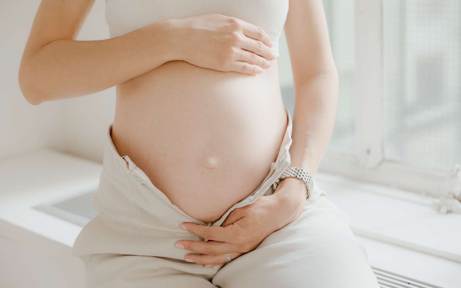 Primer plano de una mujer embarazada sosteniendo suavemente su vientre, simbolizando la maternidad y la maternidad.