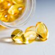 Primer plano de alta calidad de cápsulas de gelatina blanda transparentes derramadas de un frasco de vidrio, que muestran vitaminas o suplementos.