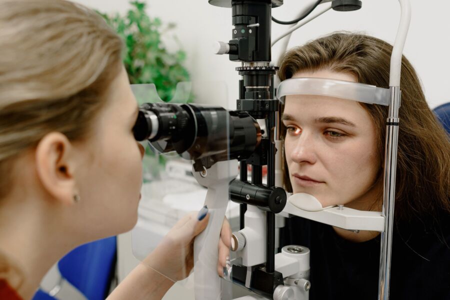 Especialista médico femenina concentrada que utiliza una herramienta profesional para controlar la visión del paciente en la clínica de oftalmología contemporánea