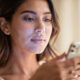 mujer con movil en la mano en primer plano con luz azul del movil reflejando sobre su cara, que el color genral de la imagen sea por el día y con luz natural