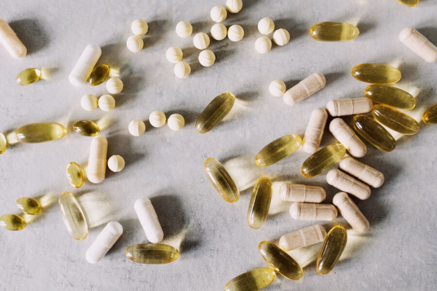 Varias vitaminas y suplementos sobre un fondo de mármol, capturados en un estilo plano.