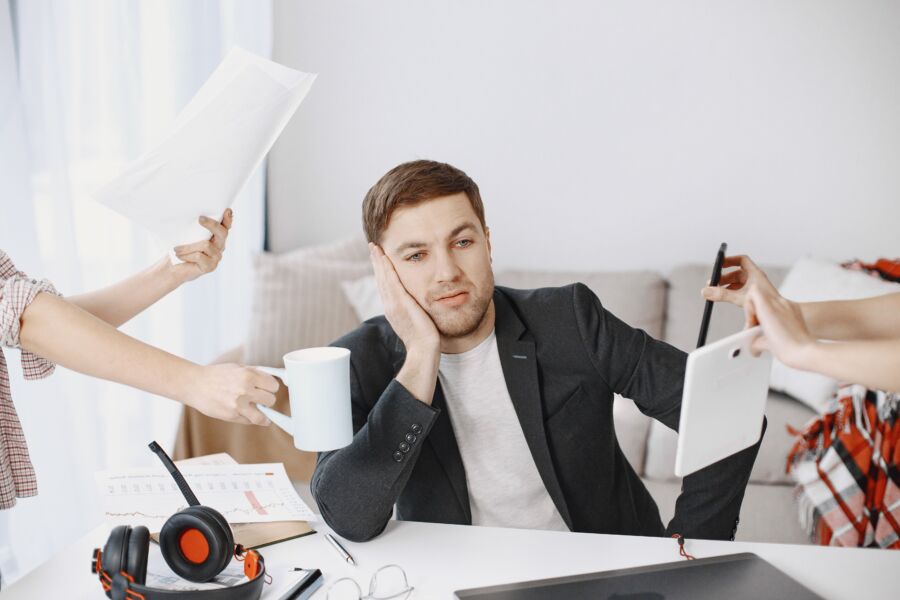 Un hombre de negocios abrumado por las tareas en un entorno de oficina moderno, que representa la multitarea y el estrés.