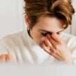 Un primer plano de una mujer frotándose los ojos, transmitiendo estrés y fatiga en el interior.