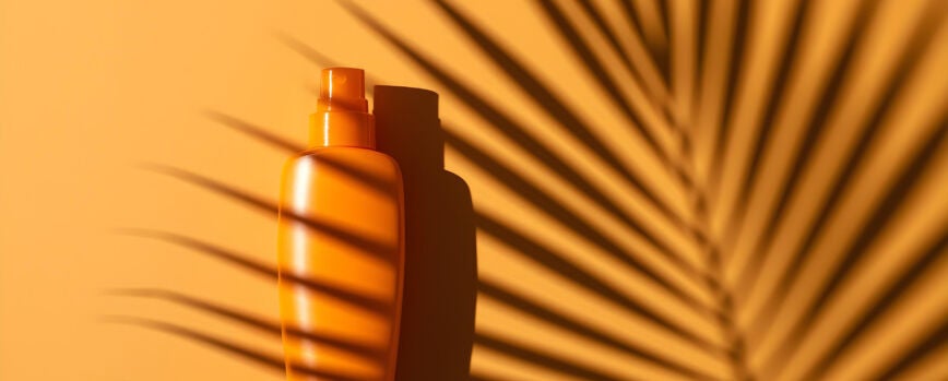 Botella de protector solar sobre un fondo naranja