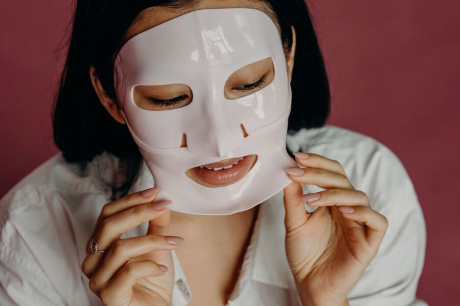 Mujer asiática que se aplica una mascarilla como parte de su rutina de cuidado de la piel, promoviendo la belleza y el autocuidado.