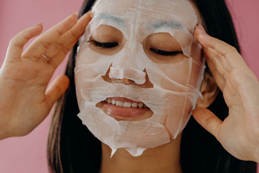 Primer plano de una mujer asiática aplicando una mascarilla hidratante para el cuidado de la piel.