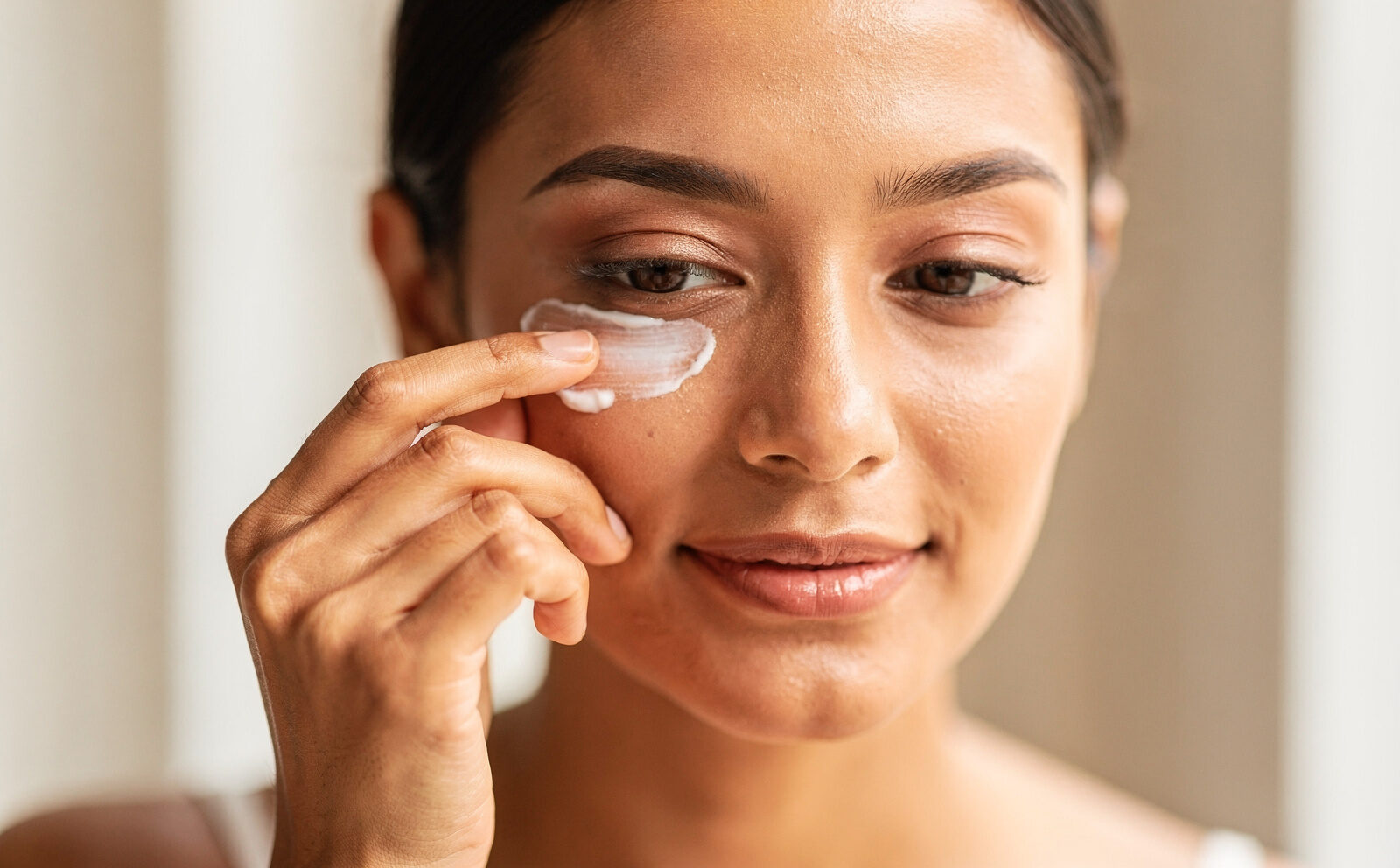 mujer aplicandose crema en el contorno de los ojos
