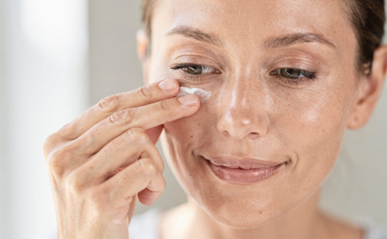 mujer se aplica crema en el contorno de los ojos