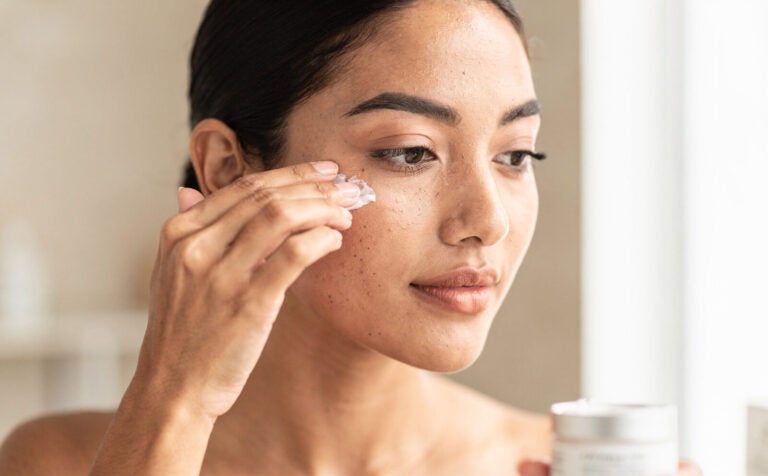 mujer se pone crema en el contorno de los ojos