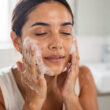 mujer se lava la cara con jabon facial
