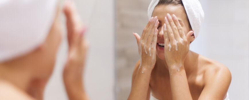 Mujer lavándose la cara en el baño.