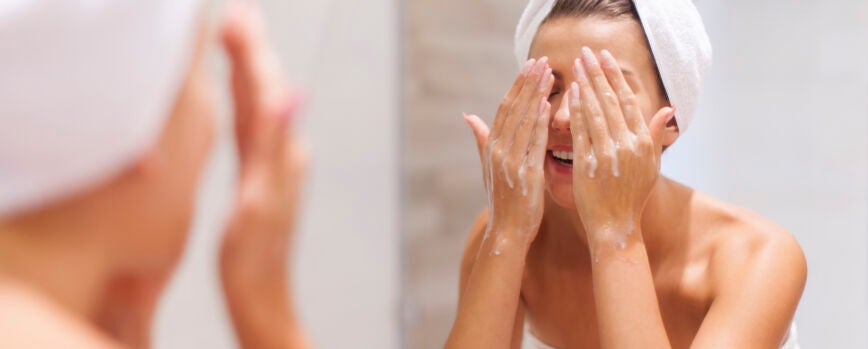 Mujer lavándose la cara en el baño.