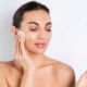 Retrato de belleza cercano de una mujer en topless con piel perfecta y maquillaje natural quitando almohadillas de algodón sobre un fondo blancox9