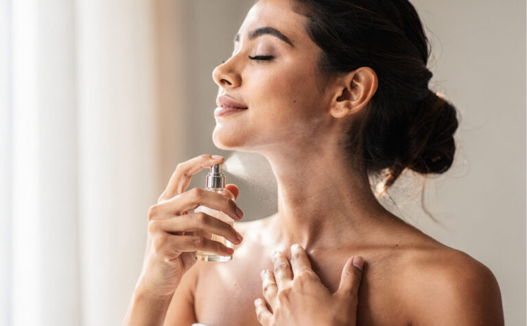 mujer se pone perfume en el cuello