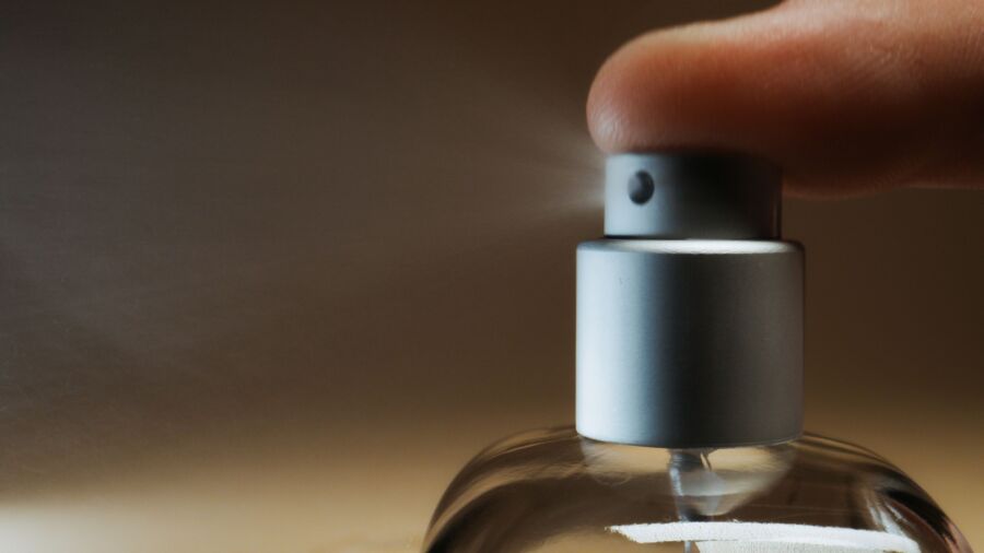 Detallado disparo capturando el dedo presionando una botella de spray de perfume, ilustrando un momento de acción.