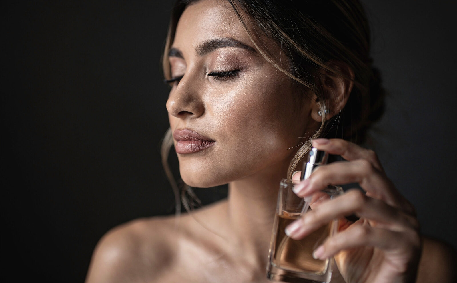 mujer se hecha perfume en un ambiente oscuro