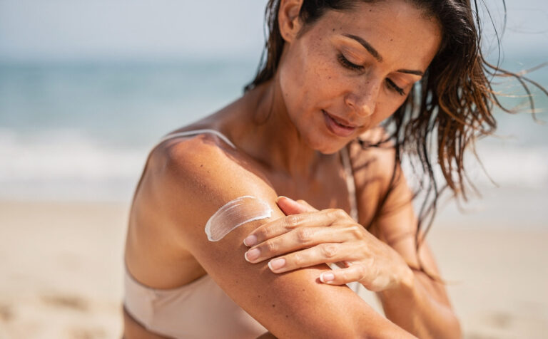 mujer en la playa se pone protector solar