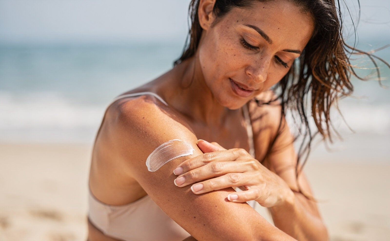 mujer en la playa se pone protector solar