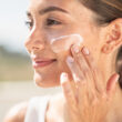 mujer poniendose protector solar en el exterior primer plano